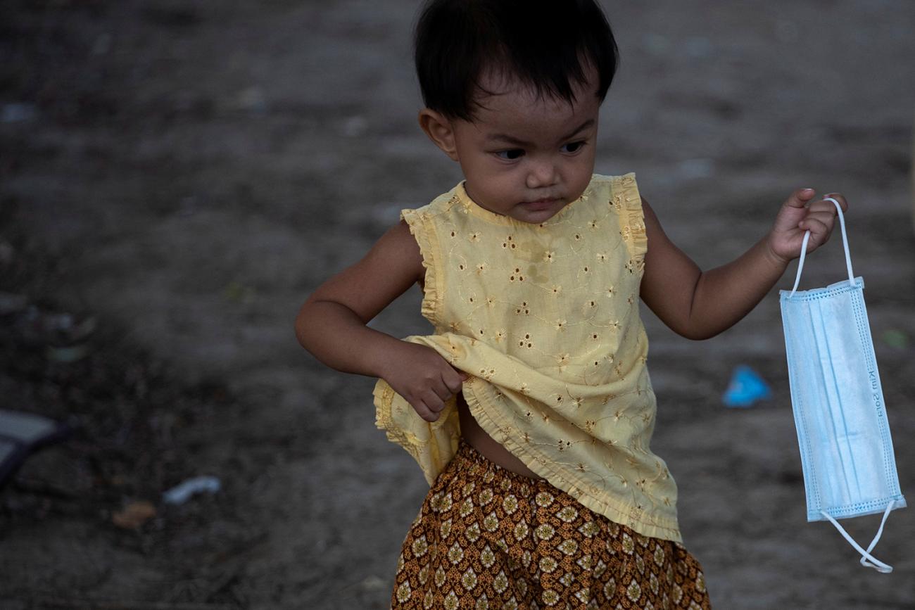 The photo shows a young girl under five carrying a facemask. It's a really cute picture. 