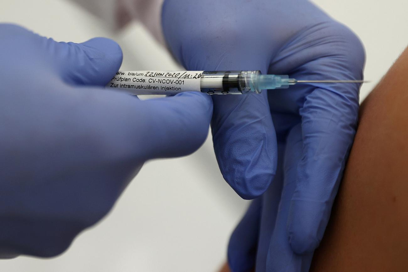The photo shows an arm receiving a jab. The hypodermic is labelled with technical information. 