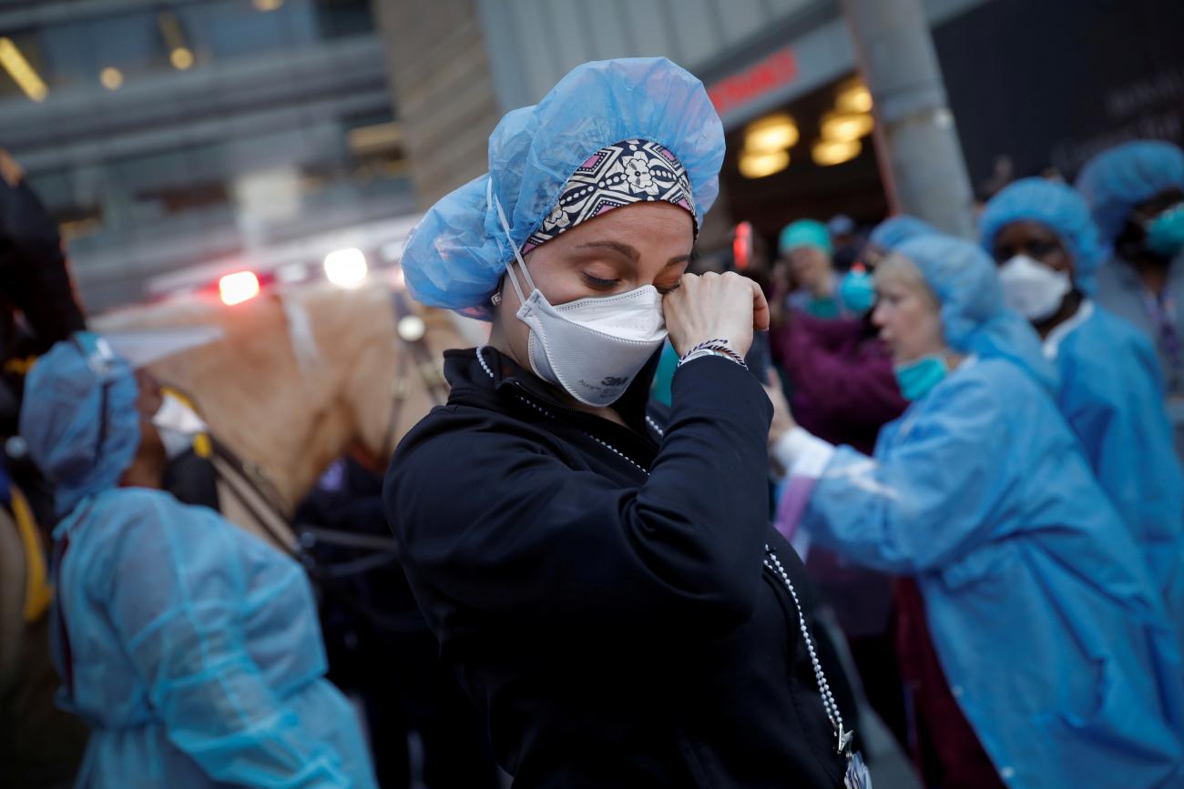A nurse wipes away tears outside NYU Langone Medical Center as police officers cheer and thank health-care workers during the COVID-19 outbreak in New York City, New York, April 16, 2020.