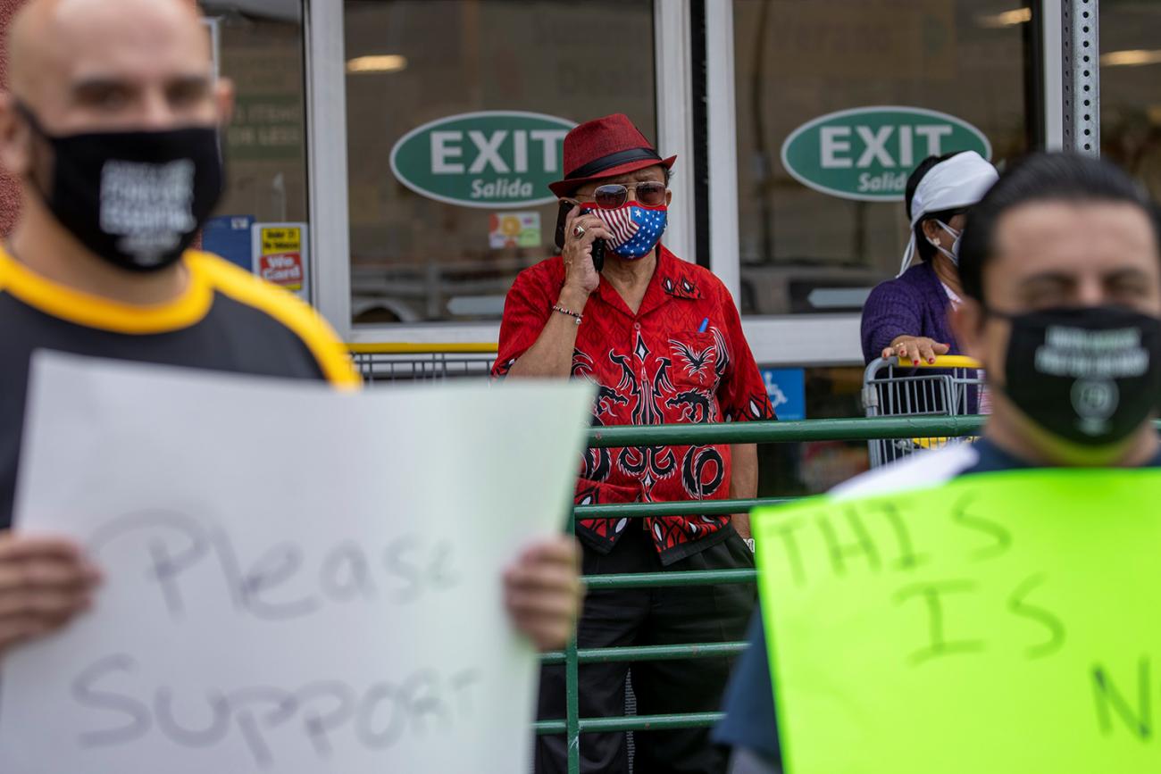The photo shows the shopper standing behind a line of protesters who are holding homemade signs. 
