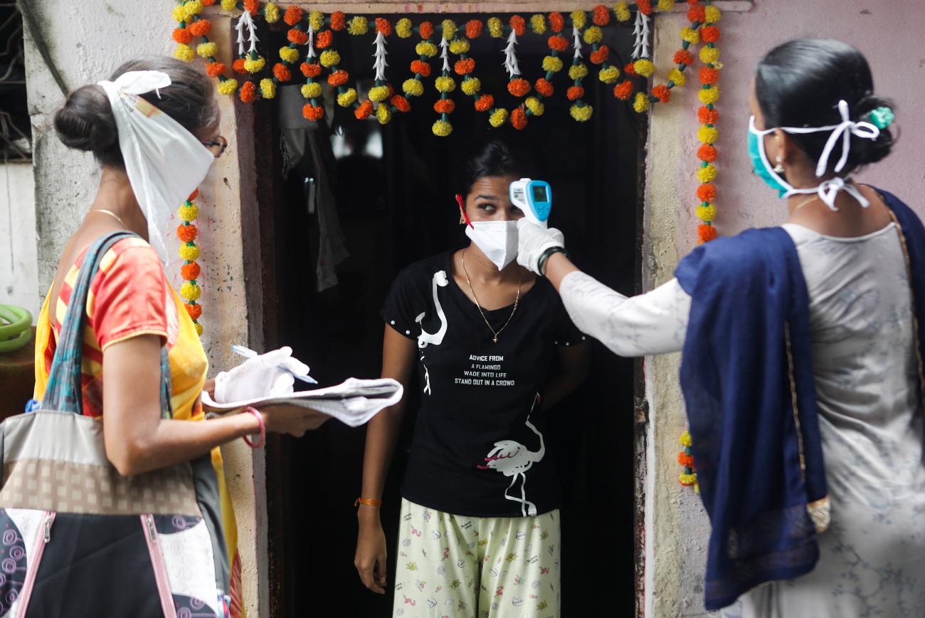 Community health volunteers check the temperature of a girl at a slum area during a check up campaign for the coronavirus disease (COVID-19) in Mumbai, India, September 16, 2020. REUTERS/Francis Mascarenhas