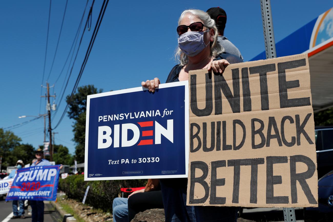 A woman holds a sign in support of Democratic presidential nominee Joe Biden as supporters of U.S. President Donald Trump gather ahead of his campaign stop in Old Forge, Pennsylvania, on August 20, 2020.