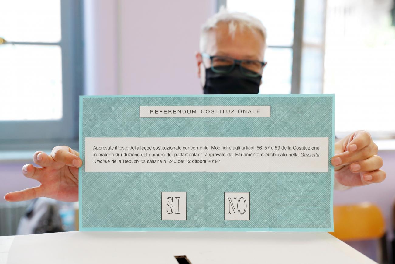 A man shows a light blue ballot paper with the option to vote "yes" or "no" during a referendum to sanction a proposed cut in the number of Italian parliamentarians at a voting center in Rome, Italy, September 20, 2020.