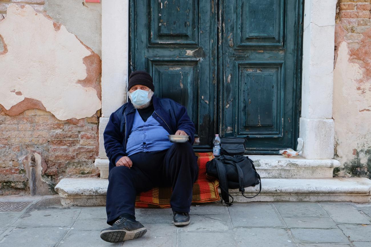 A homeless man wearing a protective mask is seen in Venice as the Italian government allows the reopening of some shops while a nationwide lockdown continues following the outbreak of the coronavirus disease (COVID-19), in Venice, Italy, April 14, 2020. 