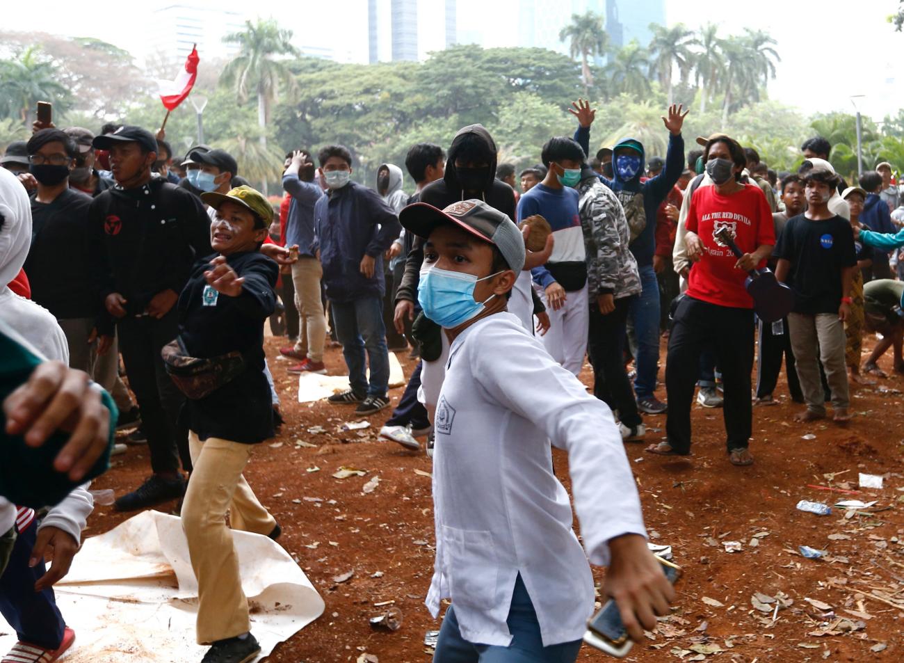 Demonstrators throw stones during a protest against the government's labor reforms bill in Jakarta, Indonesia, October 13, 2020.