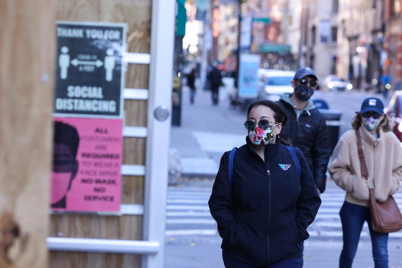 Pedestrians walk past a store with guidelines for social distance and face masks as the global outbreak of the coronavirus disease (COVID-19) continues, in New York City, U.S., November 14, 2020.