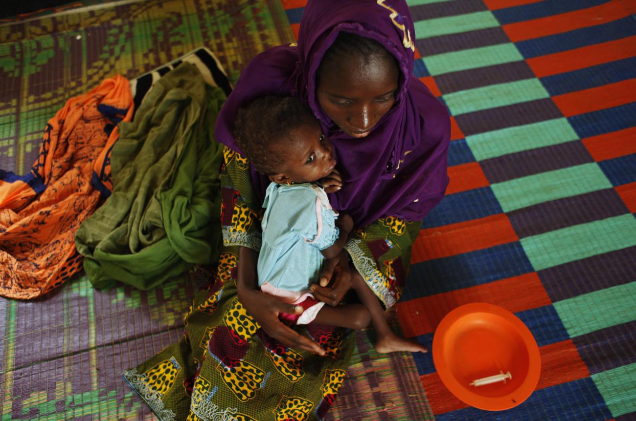 A mother, recovering from malnutrition, holds her child at a nutrition center in the Guidimakha region, Mauritania on June 3, 2012. 