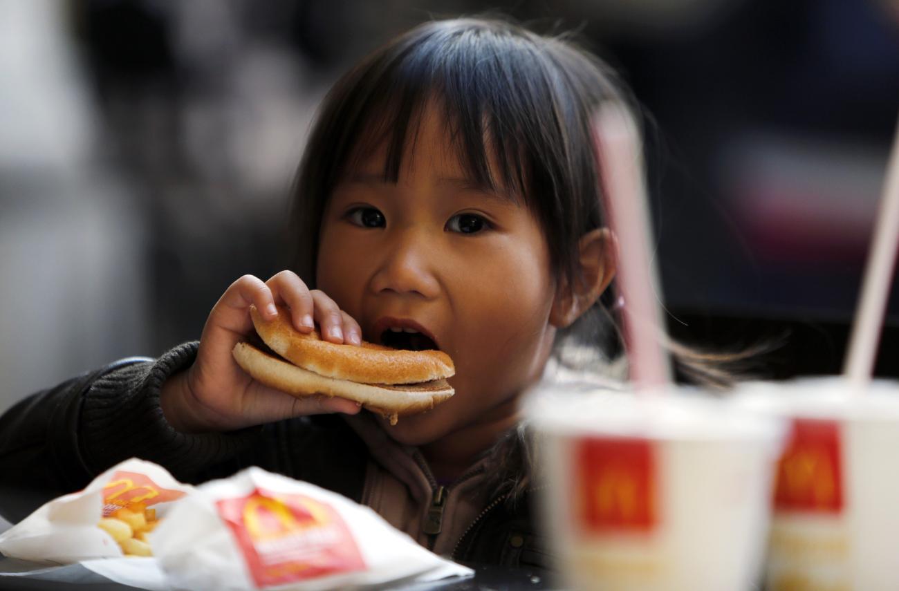A child eats a hamburger outside a fast food restaurant in downtown Milan, Italy on October 16, 2012.