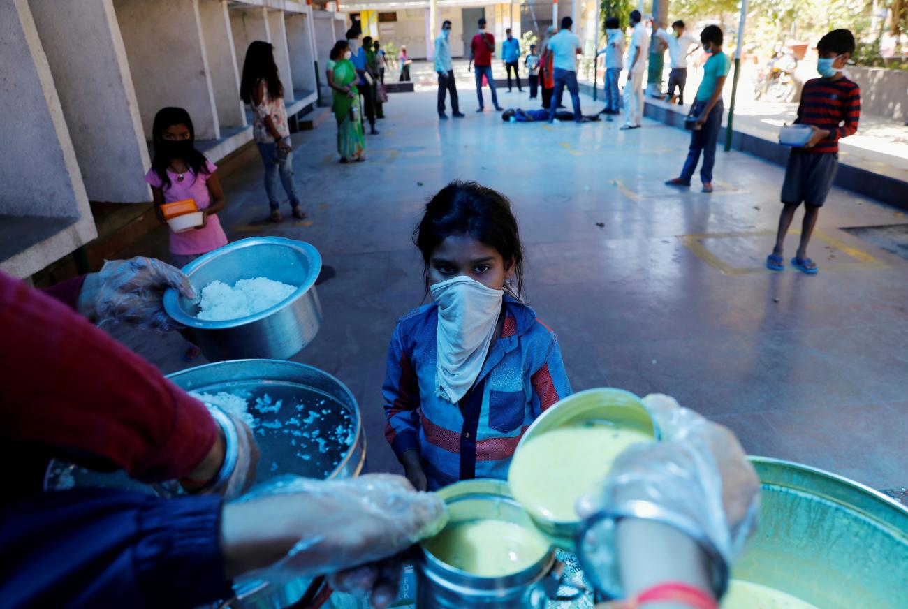 A child wearing a mask waits to receive free food being distributed by Delhi government in a school to poor people, during a 21-day nationwide lockdown to limit the spreading of coronavirus disease in Ghaziabad, on the outskirts of New Delhi, India on March 28, 2020.