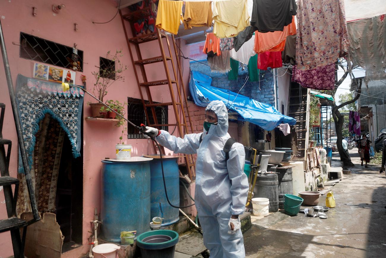 A man wearing personal protective equipment sprays disinfectant on the walls in an alley in a slum area during a lockdown to slow the spread of the coronavirus disease, in Mumbai, India on  June 29, 2020.