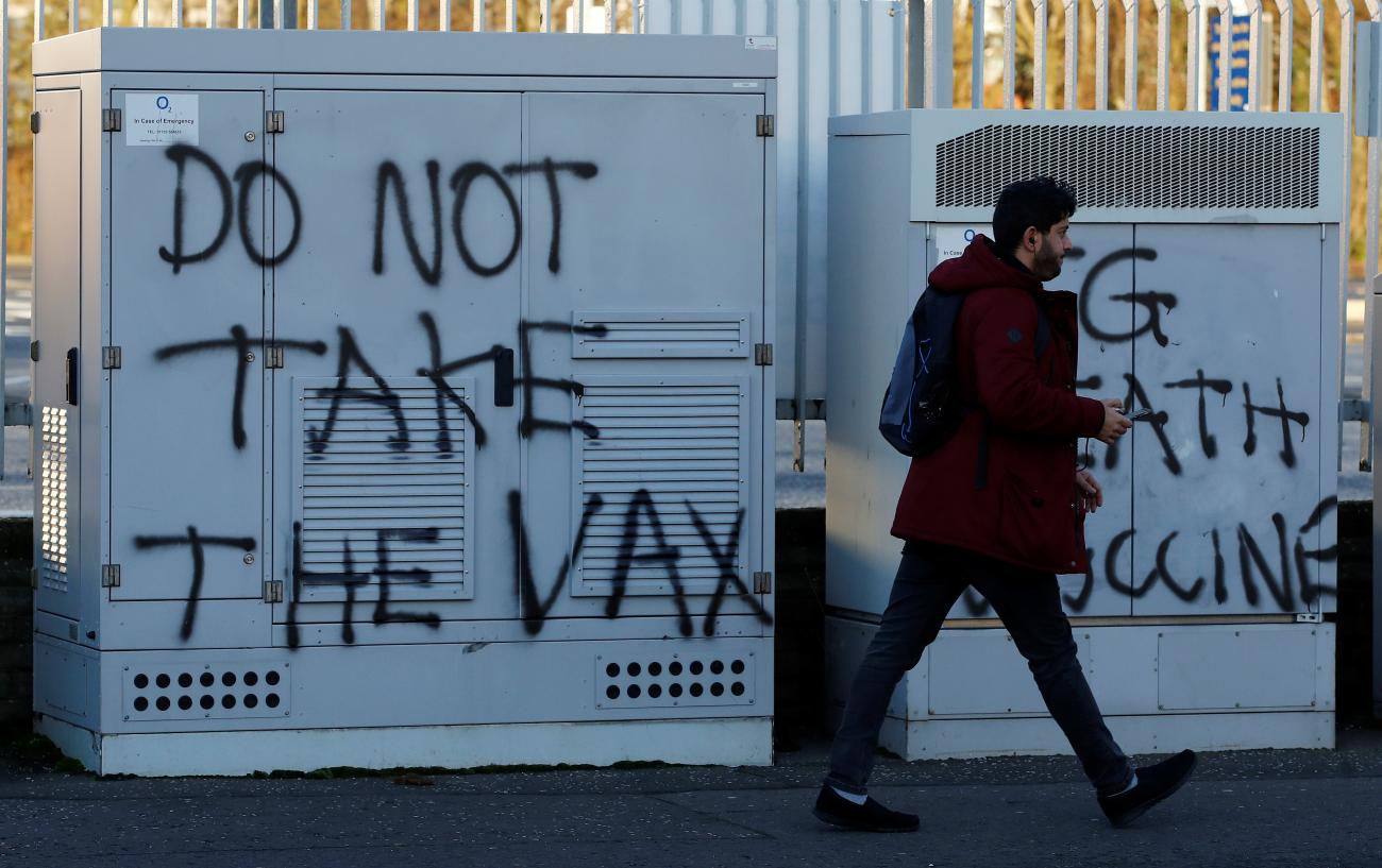 A man walks past anti-vaccine graffiti amid the outbreak of the coronavirus disease in Belfast, Northern Ireland on January 1, 2021.