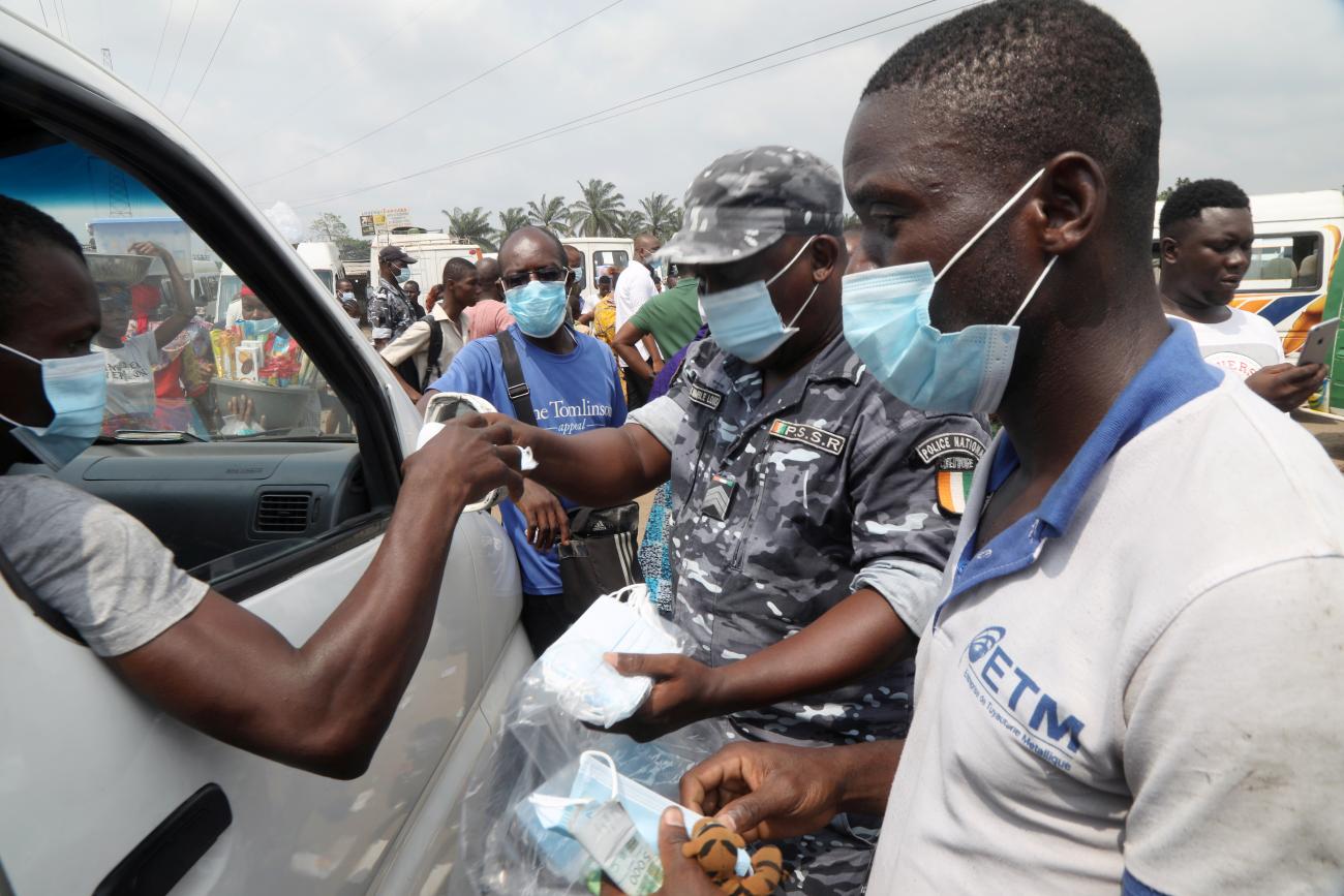 A road safety officer distributes face masks during an awareness campaign organized by the Ministry of Transport at Yopougon station in Abidjan, Ivory Coast on January 19, 2021.