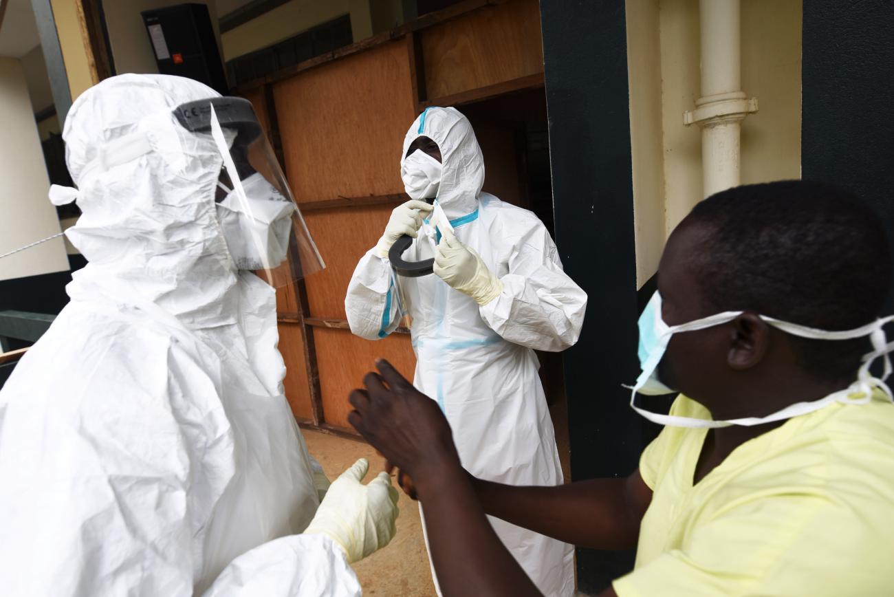 A community health officer helps sanitation workers to put on personal protective equipment (PPE) at the coronavirus treatment center of Fourah Bay College in Freetown, Sierra Leone July 2, 2020.