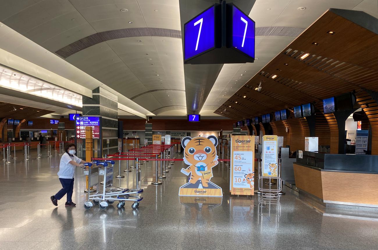 A staff member wearing a face mask following the coronavirus disease (COVID-19) outbreak pushes trolleys past empty counters at Taipei’s Taoyuan International Airport, in Taiwan July 17, 2020