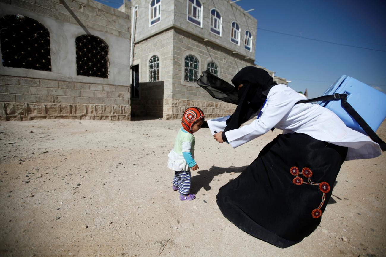 A health worker holds a girl to give her polio vaccination drops during a house-to-house anti-polio vaccination campaign in Yemen's capital Sanaa, April 12, 2016.