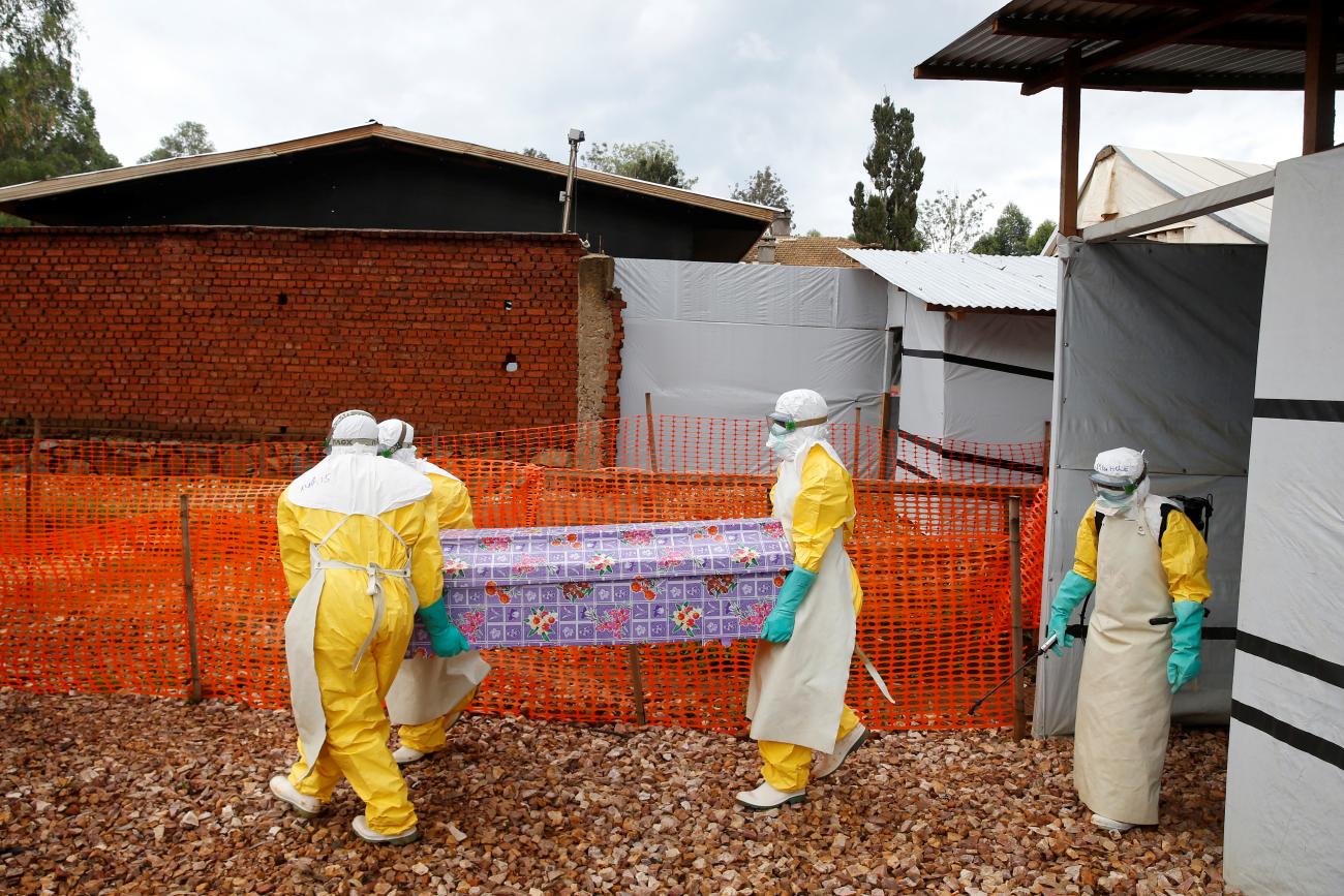 Health workers dressed in Ebola protective suits carry a coffin with the body of Congolese woman