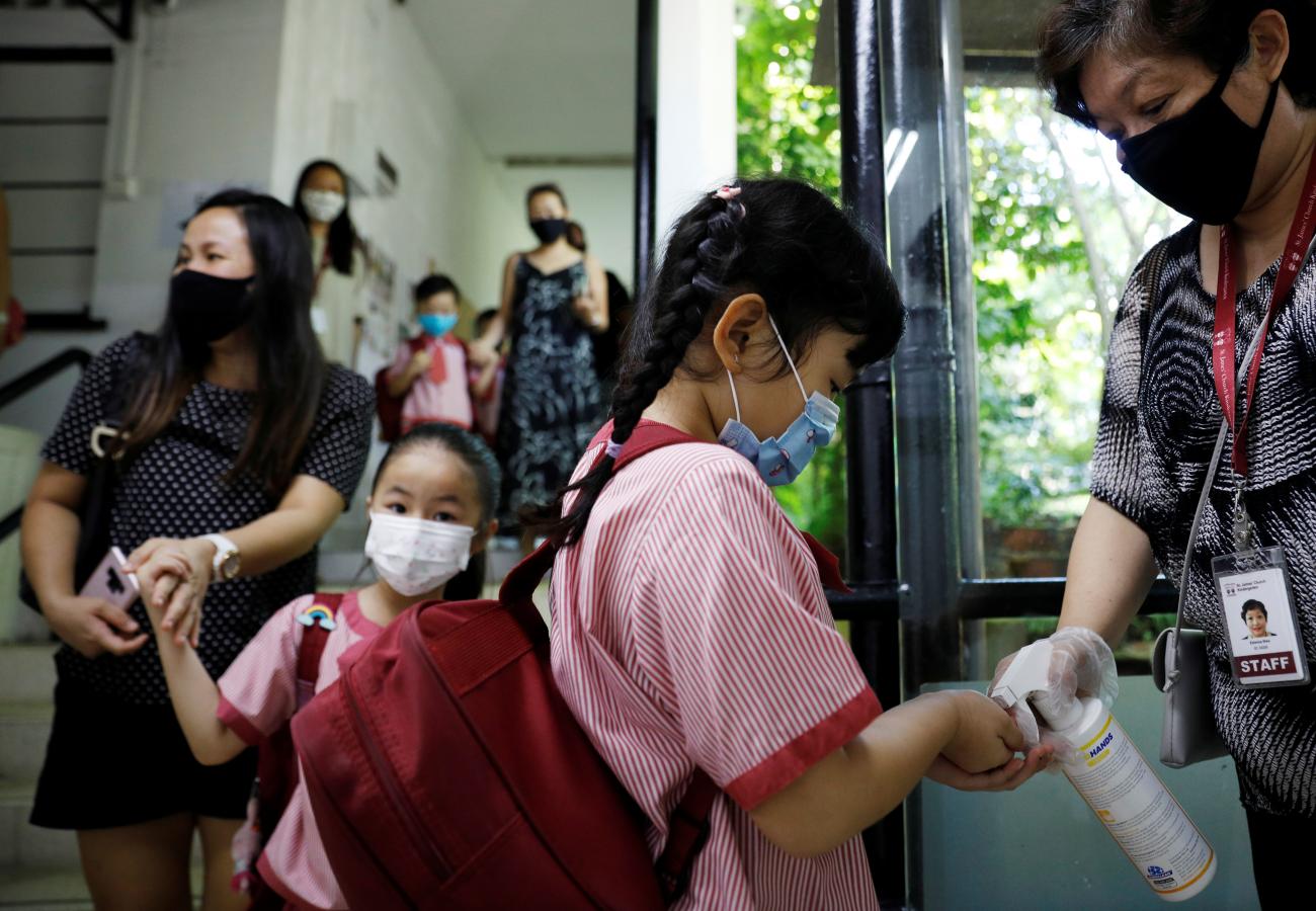 Children wearing protective face masks sanitise their hands as they attend preschool classes at St James' Church Kindergarten as schools reopen amid the coronavirus disease (COVID-19) outbreak in Singapore June 2, 2020
