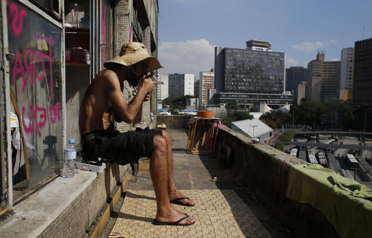 A dweller smokes a cigarette at the balkony in the centre of Sao Paulo, June 18, 2014.