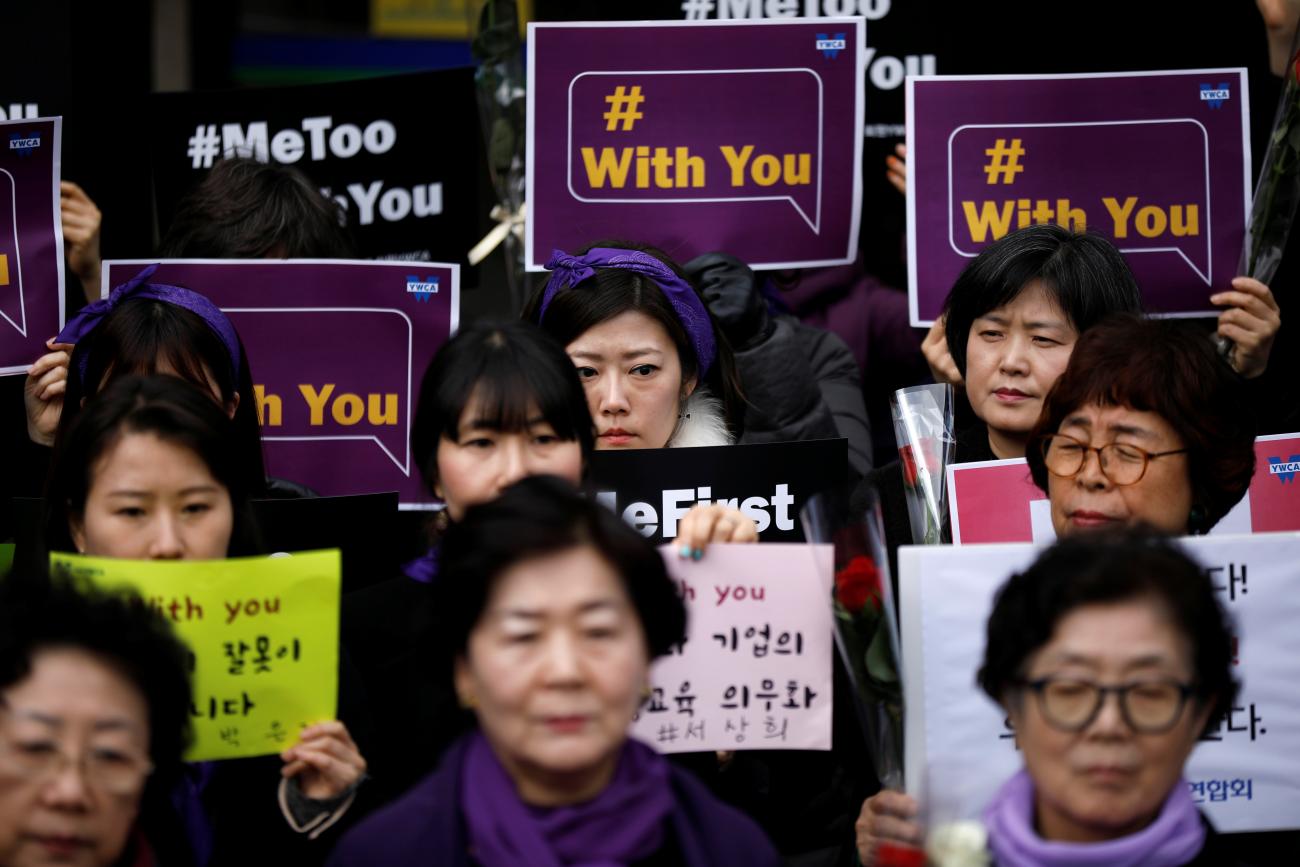 Women stand together in a crowd holding signs as they participate in a #MeToo protest on International Women's Day in Seoul, South Korea on March 8, 2018.