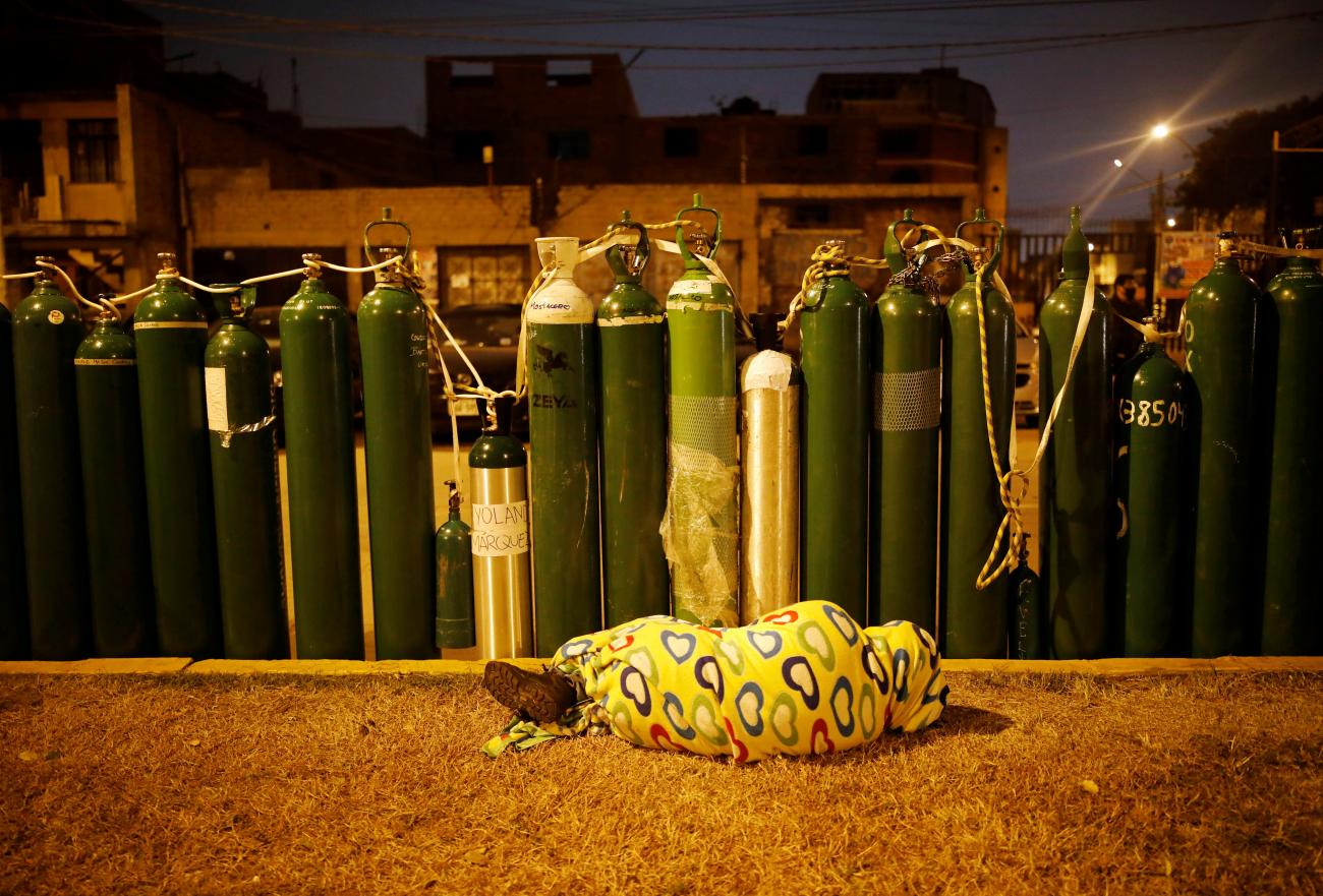 During a COVID-19 outbreak in Peru, a person sleeps next to empty oxygen tanks, saving a spot in line, in Callao, Peru on February 4, 2021. 
