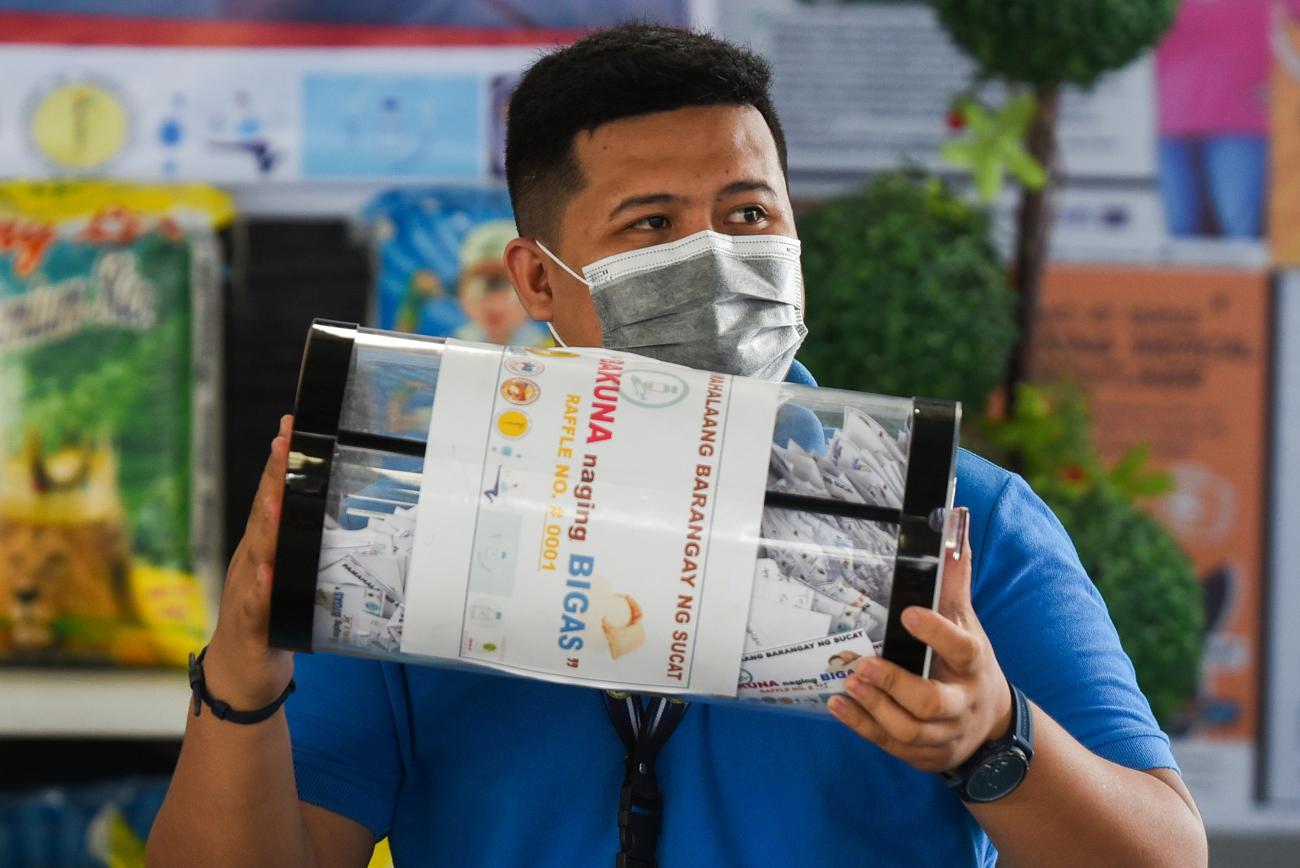 Village official Paolo Tolentino holds a large jar filled with raffle tickets during a weekly raffle draw for sacks of rice. The raffle is for residents who received COVID vaccinates, held at the Barangay Sucat Covered Court, in Muntinlupa City, Metro Manila, Philippines, June 20, 2021