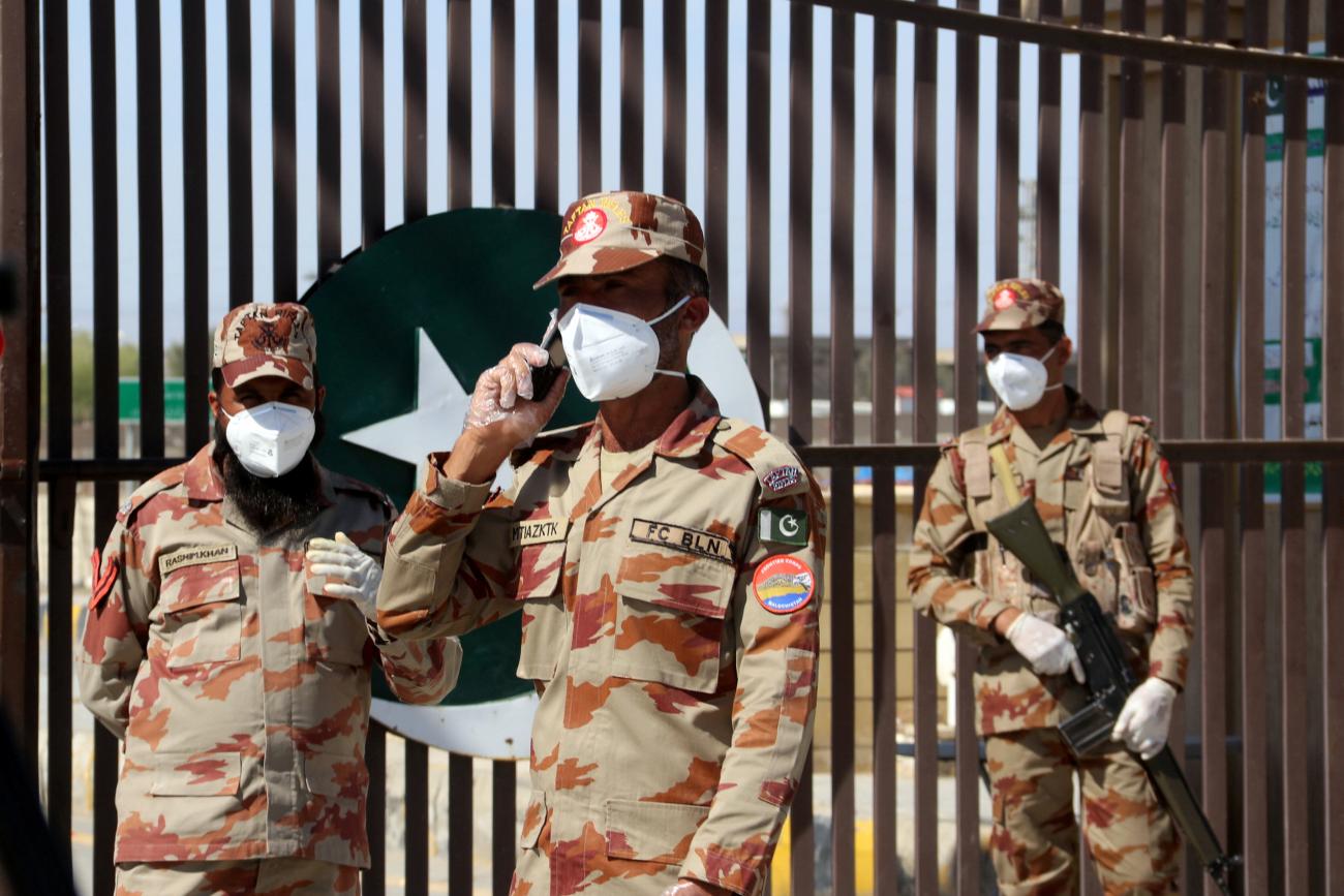 Paramilitary soldiers wear face masks as they stand in front of a closed gate of Pakistan's border post, after Pakistan sealed its border with Iran as a preventive measure following the coronavirus outbreak, at the border post in Taftan, Pakistan February 25, 2020.