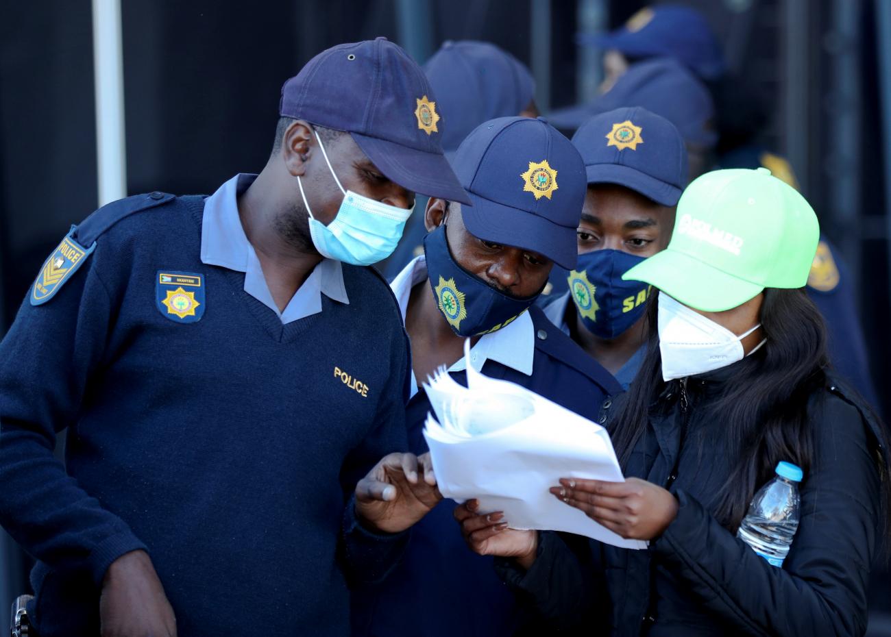 Members of the South African Police Service (SAPS) check their names on a list while waiting to receive a COVID vaccine—part of a vaccine rollout to over 180,000 SAPS members, in Soweto, South Africa on July 5, 2021. 