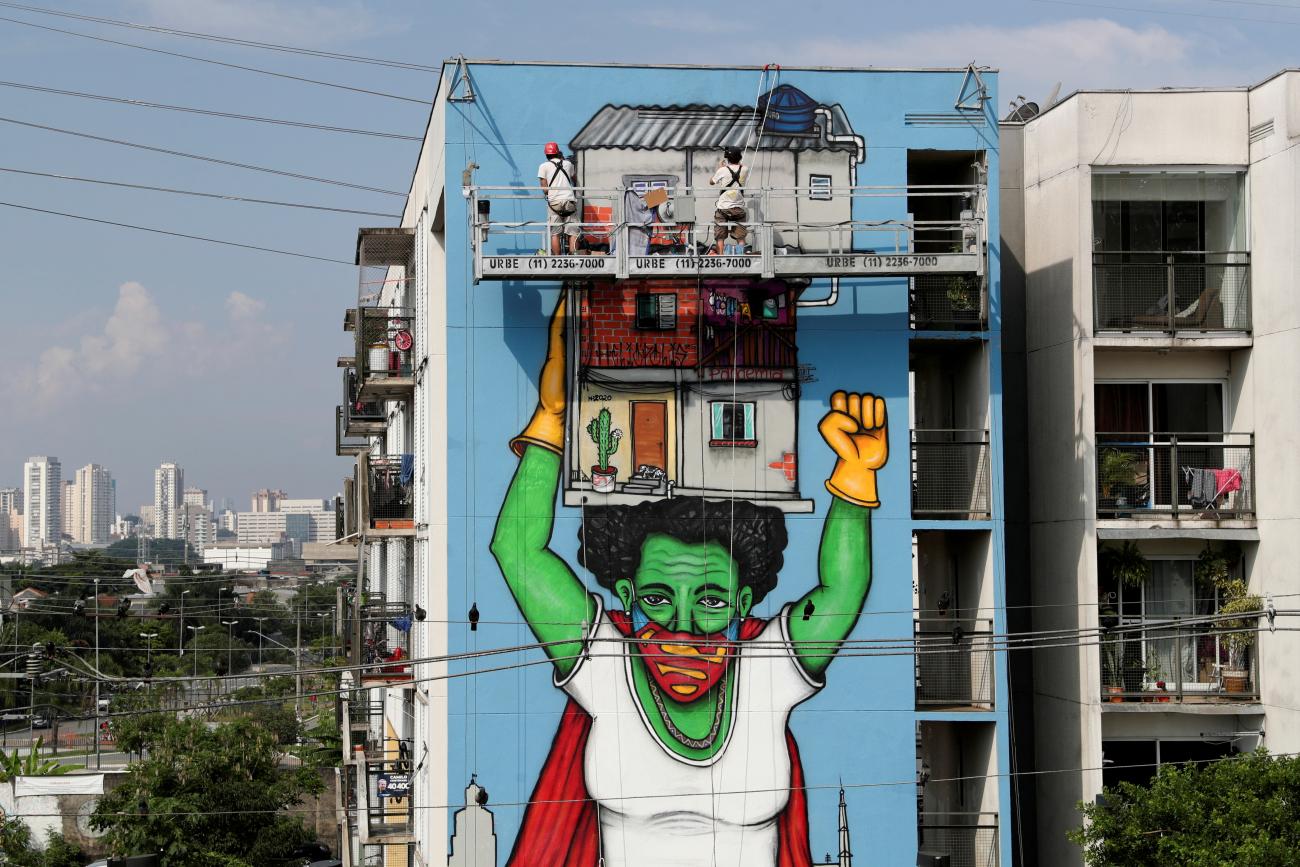 Brazilian artist Mundano stands on a platform above ground and works on street art painted on the side of a building called "Heroinas Invisiveis" (invisible heroines), a tribute to the women during the COVID pandemic, in Sao Paulo, Brazil on November 28, 2020. REUTERS/Amanda Perobelli