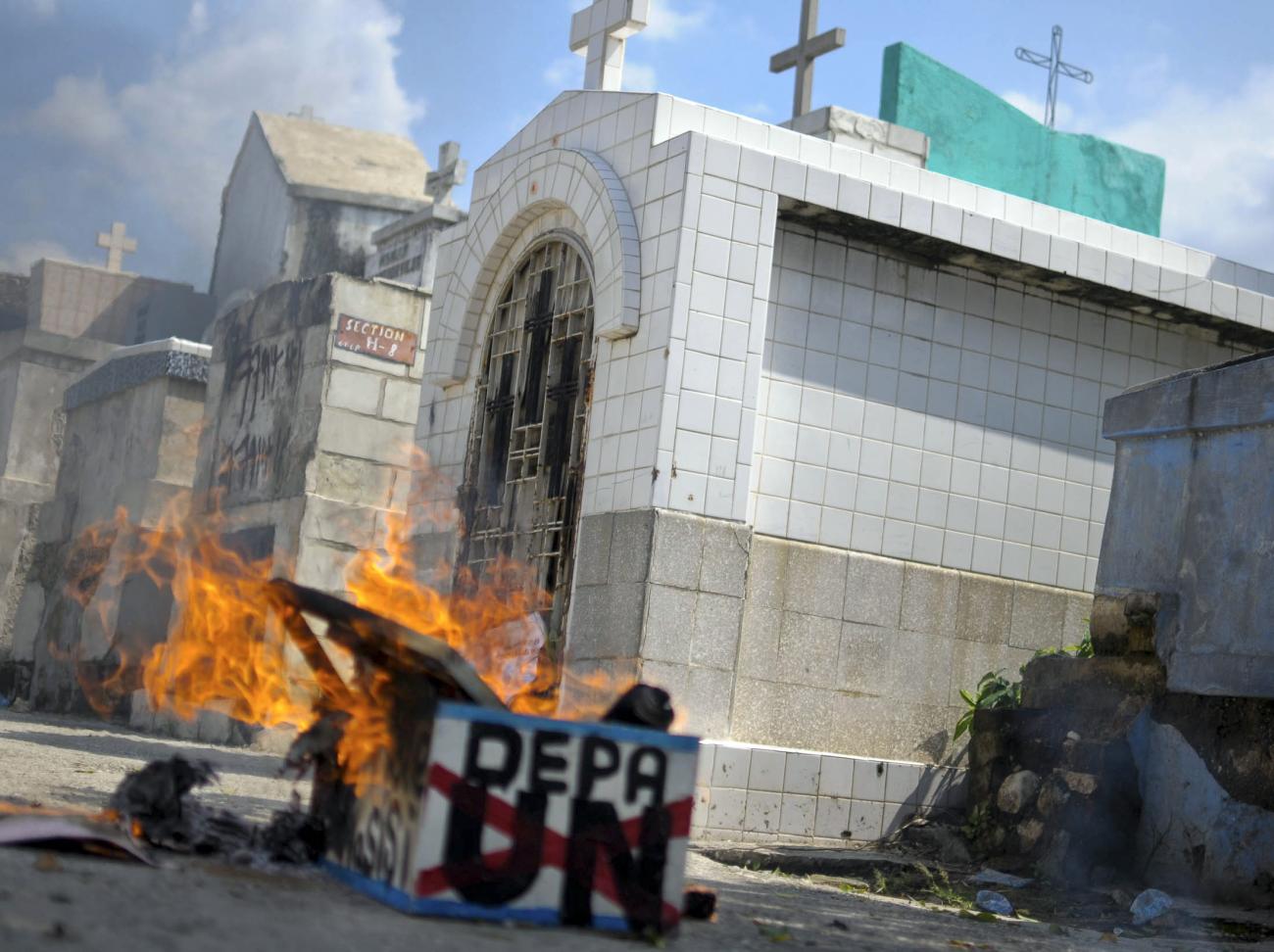 A mock coffin set on fire by demonstrators burns in a cemetery during a protest against the United Nations (UN) in Port-au-Prince October 19, 2011. The demonstrators are blaming the UN for the deaths associated with cholera in the country. 