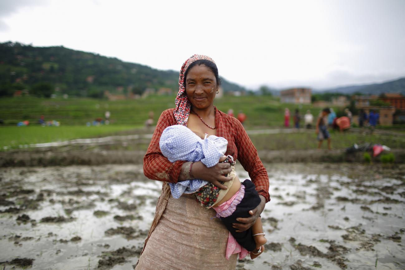 A Nepalese farmer breastfeeds her child before planting rice saplings in a rice paddy field during Asar Pandra festival in Bhaktapur June 29, 2013