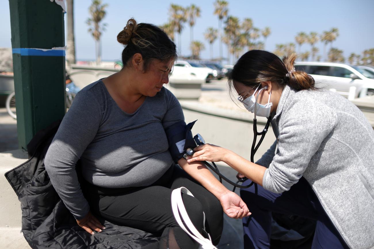 Lorena Christie, 40, who is unhoused, has her blood pressure checked as the coronavirus disease (COVID-19) disease pandemic continues, on Venice Beach in Los Angeles, California, U.S., April 20, 2021.