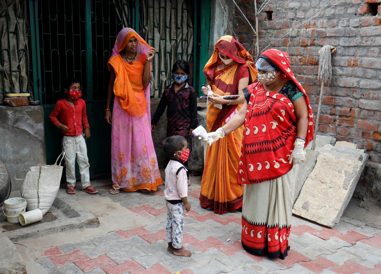 A healthcare worker checks the temperature of a child during a door-to-door surveillance to safeguard children amidst the spread of the coronavirus disease (COVID-19), at a village on the outskirts of Ahmedabad, India, June 9, 2021.