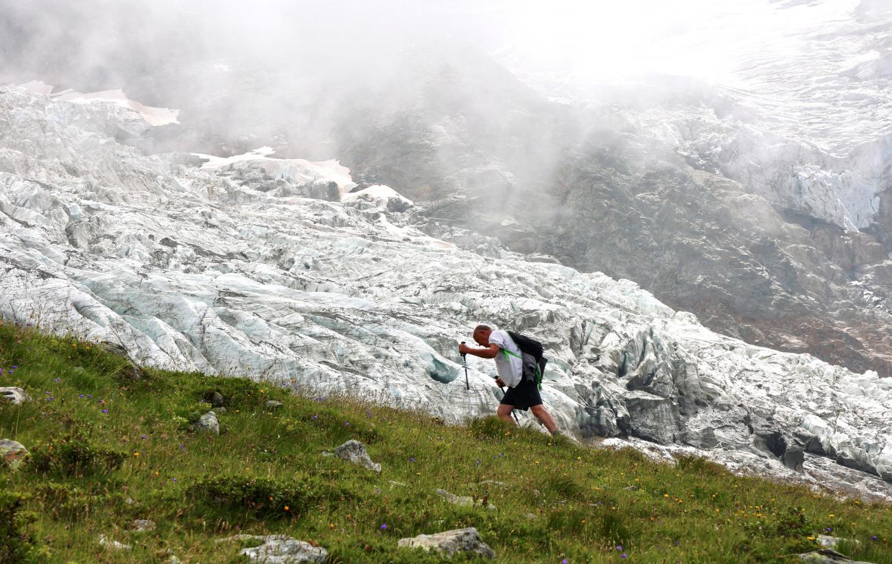 A hiker walks past the Bionnassay glacier, the smallest glacier of the Mont Blanc complex in France, which is shrinking under the the influence of global warming, according to many scientists, August 18, 2021