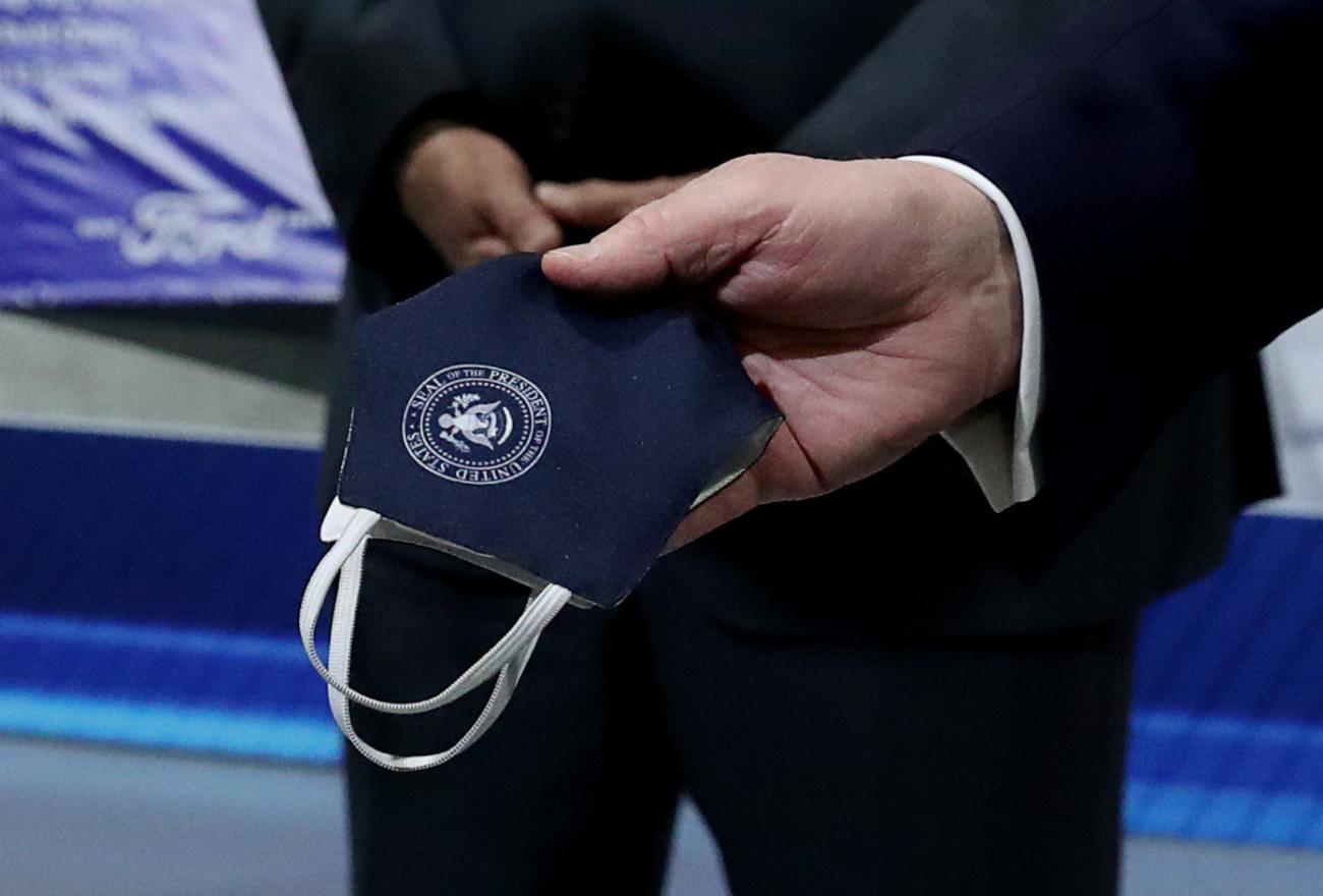 Former President Donald Trump holds a face mask behind his back that he said he had been wearing earlier during a tour at Ford Rawsonville Components Plant which manufactures ventilators and masks, in Ypsilanti, Michigan on May 21, 2020.