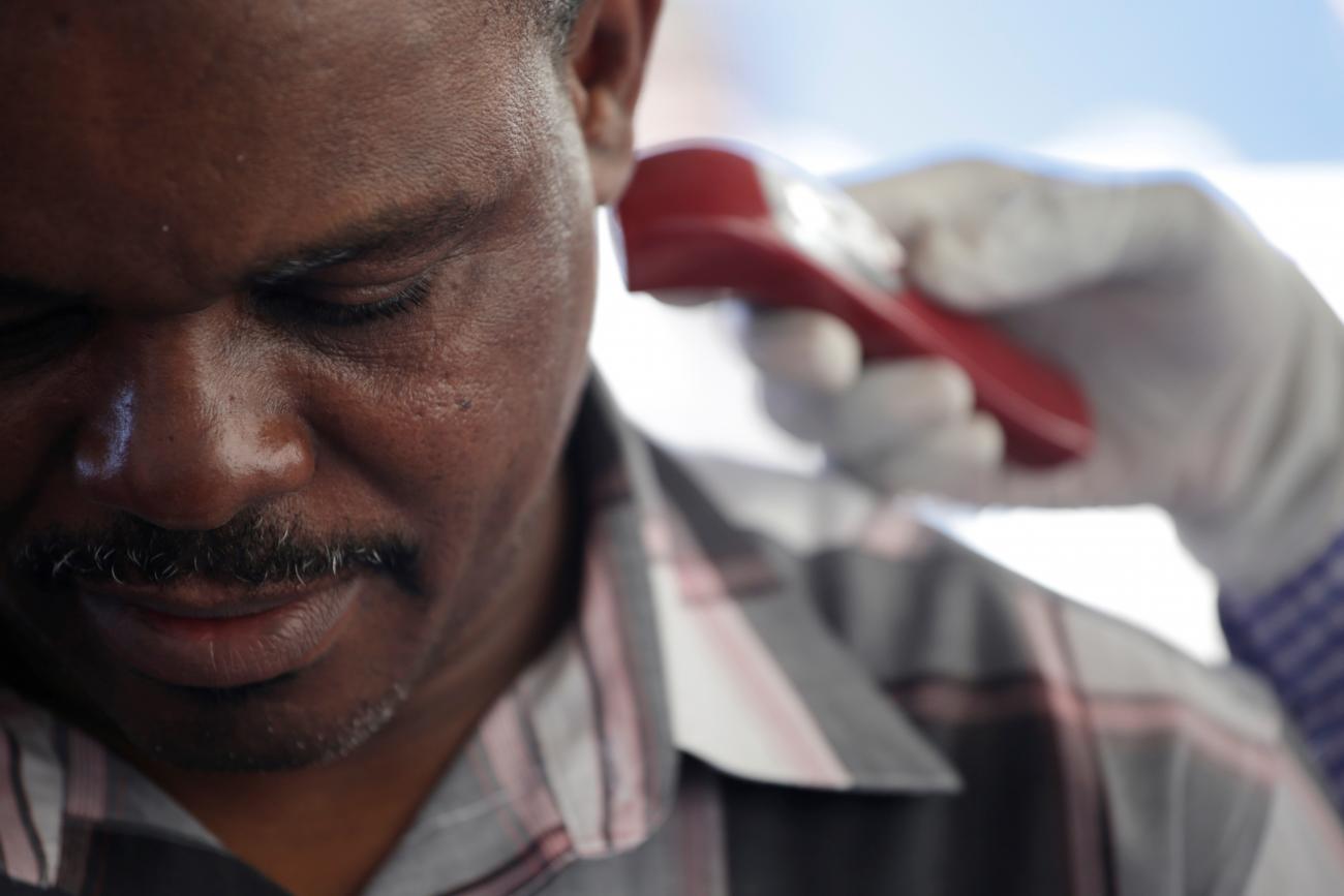 A health worker with Haiti's Ministry of Public Health and Population checks the temperature using an ear thermometer of a citizen coming from the Dominican Republic to monitor COVID at the border of Malpasse, Haiti, on March 5, 2020.