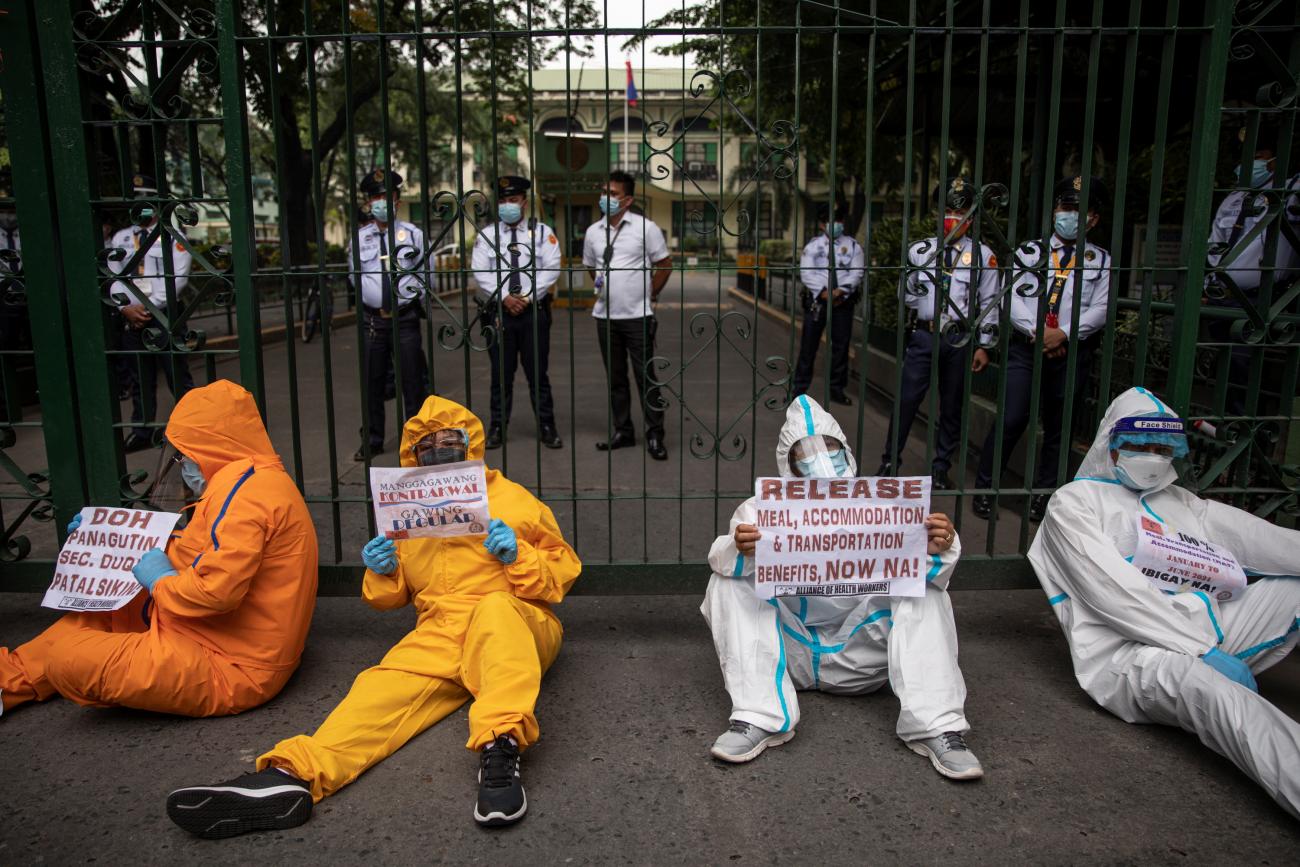 Health-care workers in white, orange, and yellow protective medical clothing protest outside the Philippines' Department of Health, demanding better wages and benefits amid rising COVID-19 cases, in Manila, Philippines, on September 1, 2021.