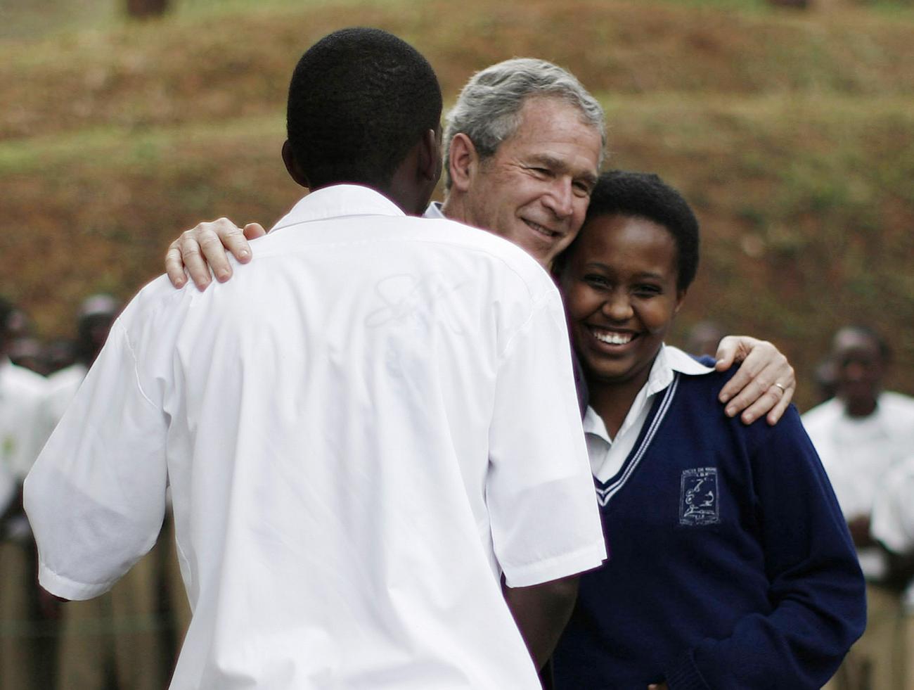 U.S. President George W. Bush hugs two students who had just performed a play for him on the subject of abstaining from sex as a way to avoid HIV/AIDS and teenage pregnancy, during his visit to the Lycee de Kigali school in Kigali, Rwanda, February 19, 2008.