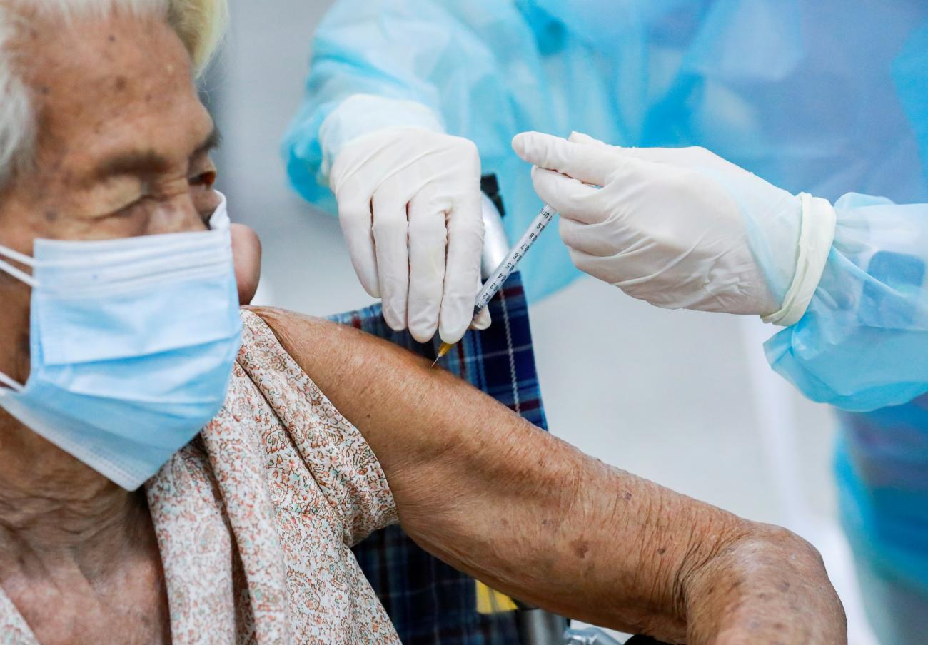 An elderly woman lifts her slender arm to receive a vaccine from a health worker as Thailand opens walk-in visits for elders, people with a minimum weight of 100 kilograms, and pregnant women, in Bangkok, Thailand, on July 26, 2021.