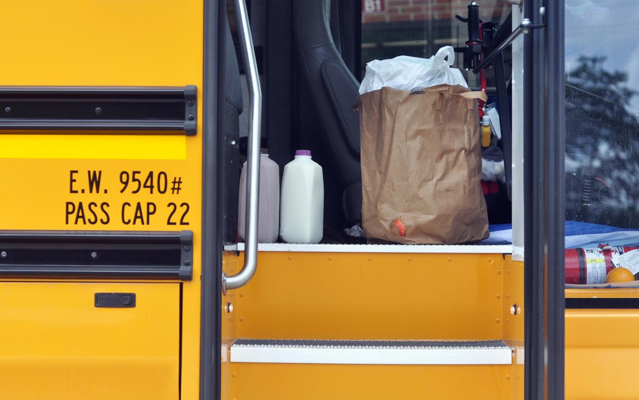 A brown grocery bag of prepared food and bottles of regular and chocolate milk sit just inside the door of a bright yellow school bus in Gurnee, Illinois, on June 29, 2021.