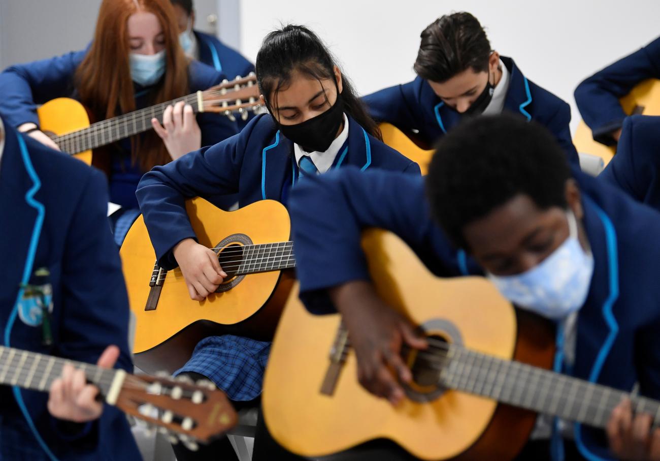 Year 9 students wear protective face masks as they take part in a guitar lesson on the first day back at school at Harris Academy Sutton, in London, Britain, on March 8, 2021.