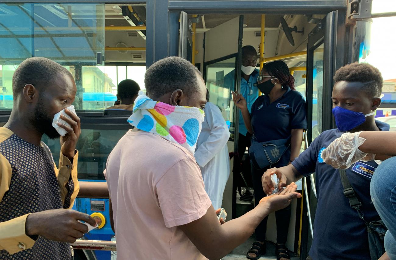Public transport bus staff offers hand-santizer to a passenger who is about to board the bus on the first day of the easing of the lockdown measures during the outbreak of the coronavirus disease (COVID-19) in Lagos, Nigeria May 4, 2020.