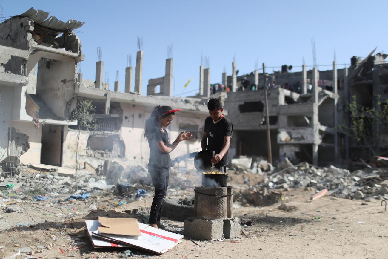 A Palestinian boy prepares corn near the rubble of houses that were destroyed in Israeli air strikes during Israeli-Palestinian fighting, in Gaza June 9, 2021.