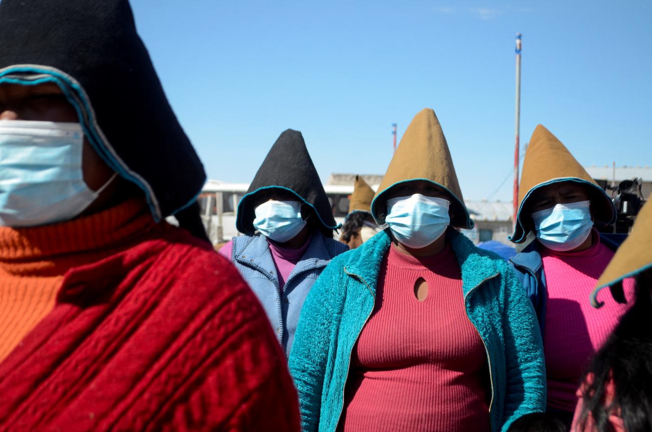 Women stand together while listening to a speaker at a health fair as others had been waiting to get vaccinated against COVID-19, in Uru Chipaya, Bolivia, on July 23, 2021. 