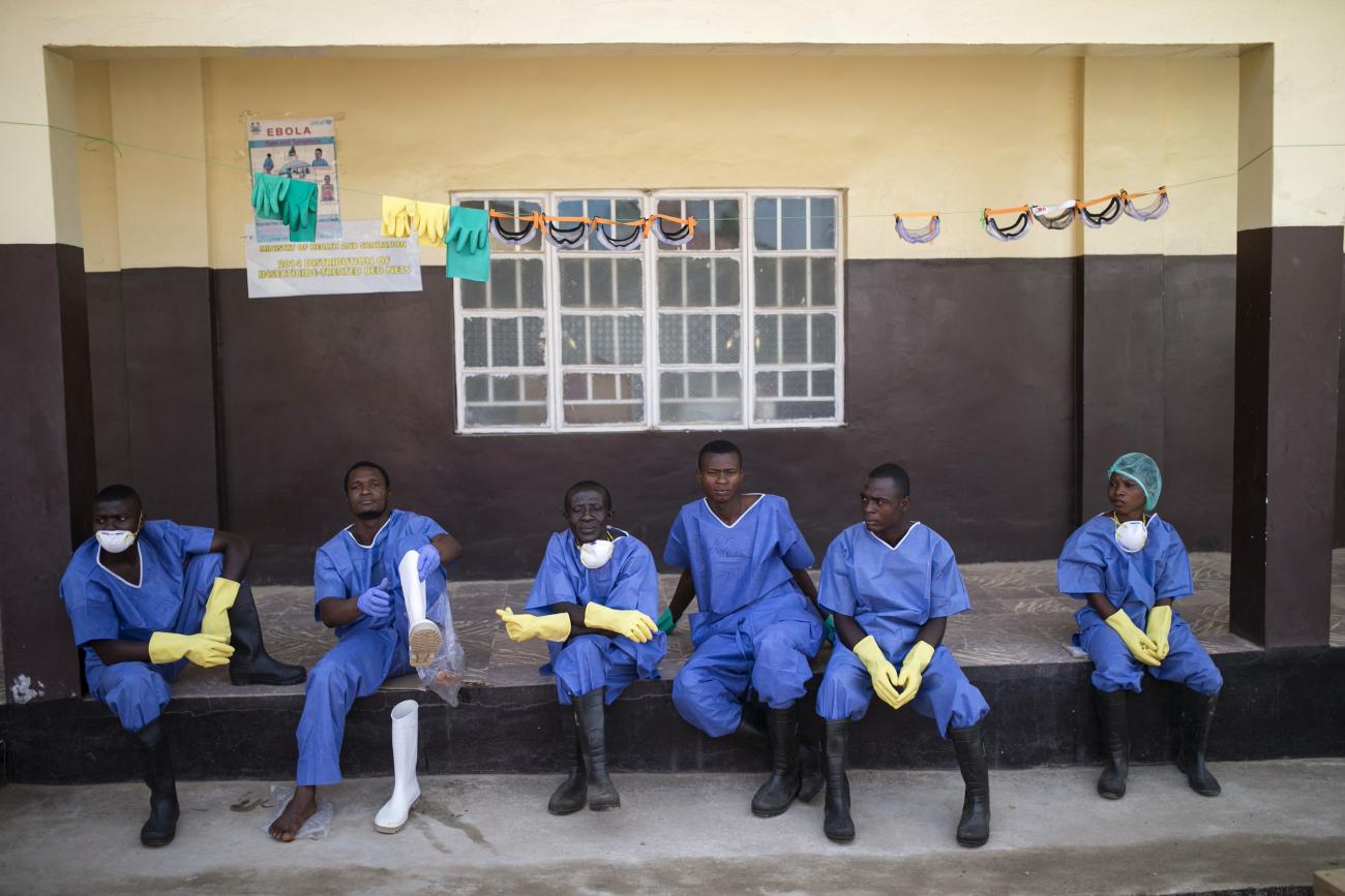 Health workers rest outside an Ebola quarantine zone at a Red Cross facility in the town of Koidu, Kono district, in Eastern Sierra Leone, on December 19, 2014.