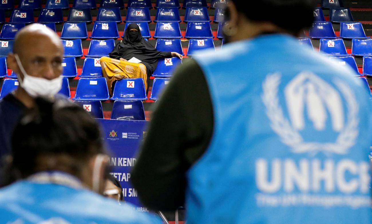 A woman waits at a sports hall for a COVID-19 vaccine during a mass vaccination program for asylum seekers and refugees in Jakarta, Indonesia, on October 7, 2021.