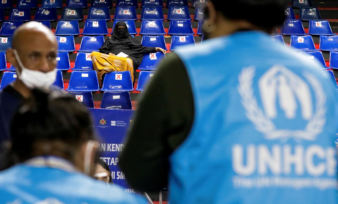 A woman waits at a sports hall for a COVID-19 vaccine during a mass vaccination program for asylum seekers and refugees in Jakarta, Indonesia, on October 7, 2021. 