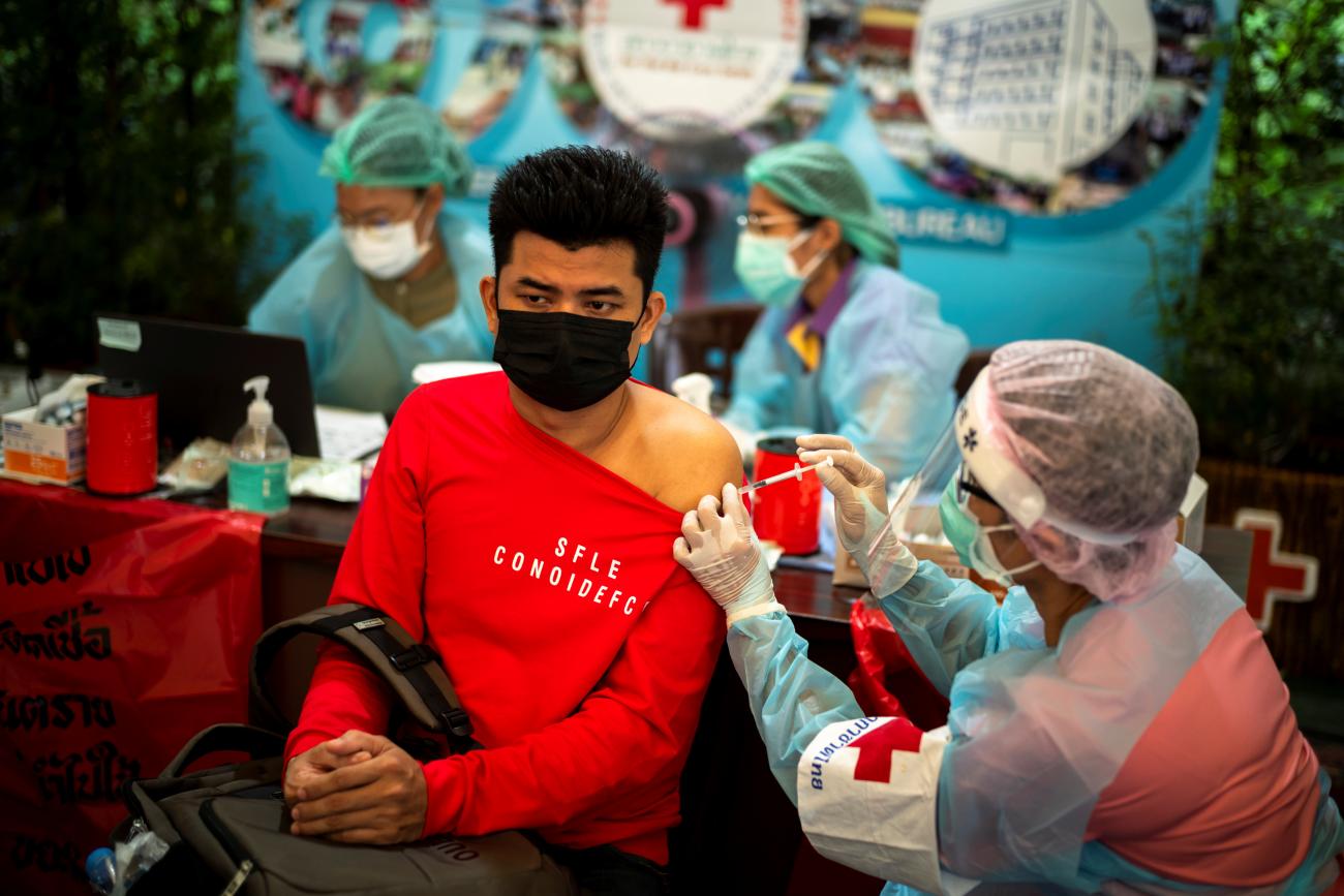 A migrant worker sits next. to a health care worker as he receives his first COVID Sinopharm vaccine at Thailand's Red Cross center in Bangkok, Thailand, on October 5, 2021.
