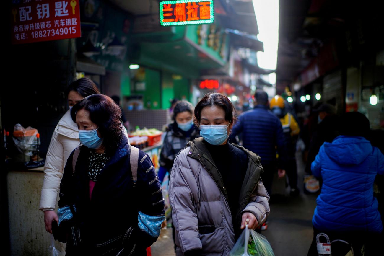 People wearing face masks walk on a street market in the early months of the outbreak of the coronavirus disease (COVID-19) in Wuhan, Hubei province, China Feb 8, 2021.