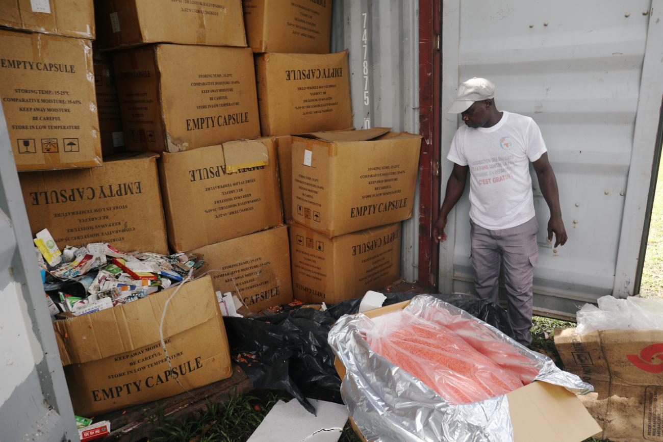 An agent in a white t-shirt and hat stands next to stacks of brown boxes full of illegal and false drugs seized by Ivorian authorities in Abidjan, Ivory Coast, on November 6, 2018. 