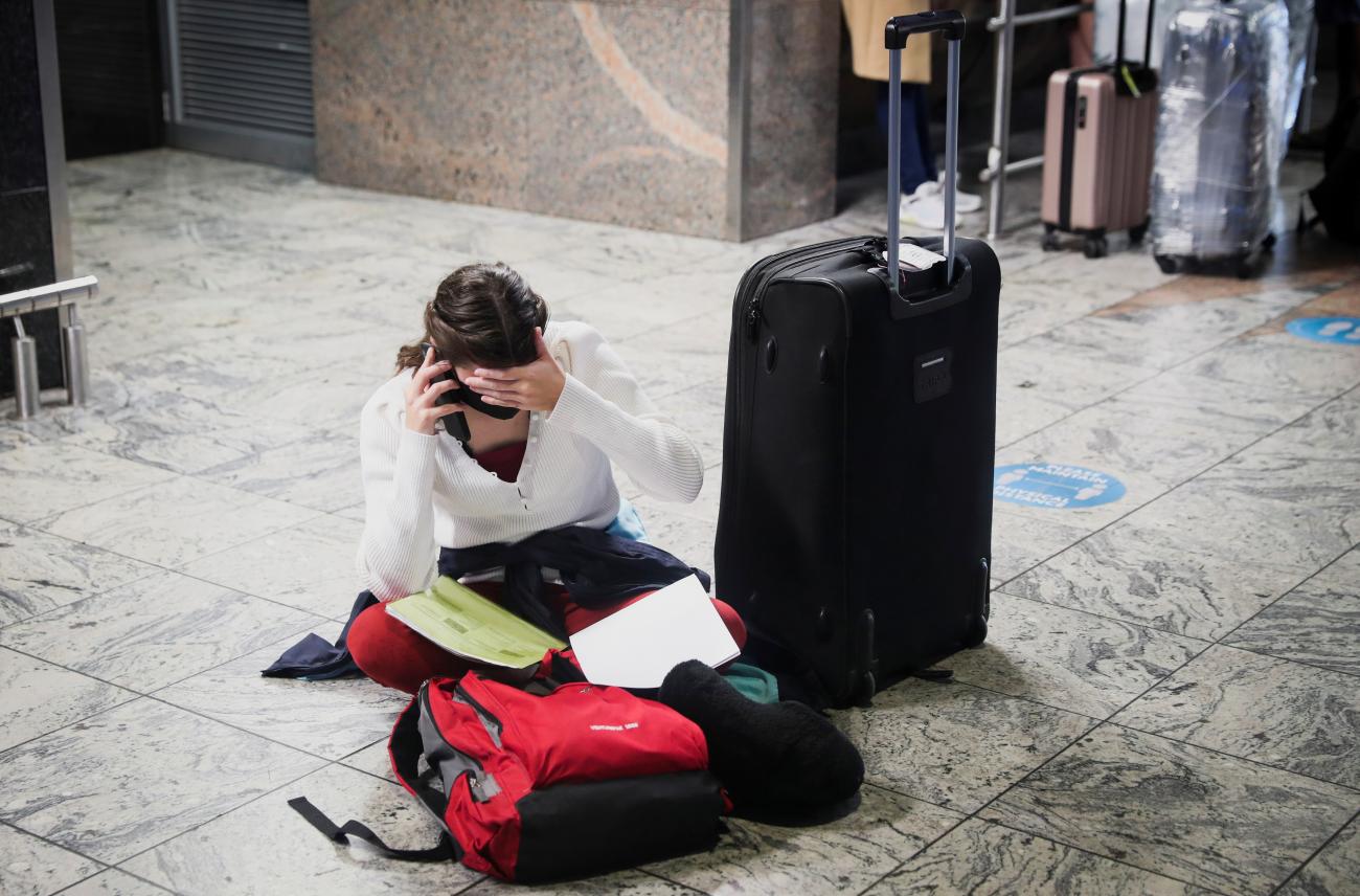 A passenger sits on the floor next to her luggage looking stressed out as she tries to find a flight out after a new SARS-CoV-2 Omicron variant is announced. Photo taken at Johannesburg OR Tambo International Airport, in South Africa, on November 28, 2021. 